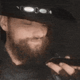 a man with a beard is wearing a black hat