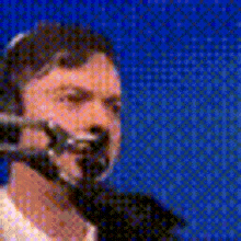 a man wearing a headset is talking into a microphone on a blue background .