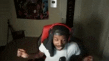 a man wearing headphones and a headband is sitting in a gaming chair .