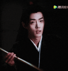 a man holding a stick with chinese characters on the bottom right