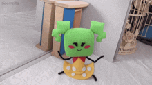 a green and yellow stuffed animal with the word goomzilla on the bottom right corner