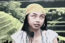 a woman wearing a head scarf and earrings is making a funny face .