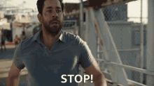a man in a blue shirt says stop in front of a bridge