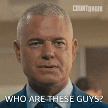 a man in a suit and tie asks " who are these guys "