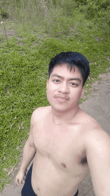 a shirtless man takes a selfie in a field of grass