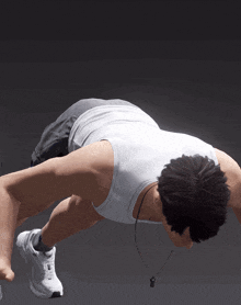 a man in a white tank top is doing a push up