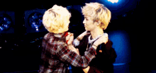 two men are hugging each other and one is holding a microphone in his hand .