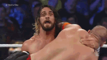 a man is wrestling another man in a wrestling match while a crowd watches .