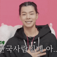 a man wearing a black hoodie with korean writing on the bottom right