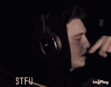 a man wearing headphones and a black hoodie has stfu written on the bottom right