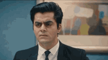 a man in a suit and tie is making a funny face in front of a picture .