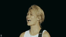 a man with blonde hair is wearing a white tank top and a black strap with the letter d on it