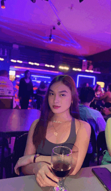 a woman is sitting at a table with a glass of wine