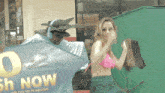 a woman in a bikini is standing next to a man in a cape and a sign that says cash now