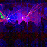 a crowd of people watching a laser show in a dark room .