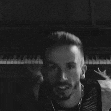 a black and white photo of a man covering his face with his hands while wearing rings .