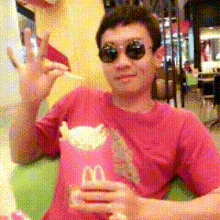 a man wearing sunglasses and a pink mcdonald 's shirt is holding a bag of french fries