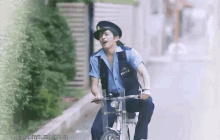 a man in a police uniform is riding a bicycle down a street