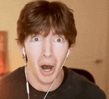 a young man wearing ear buds makes a surprised face