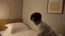 a man in a white robe sits on a bed in a bedroom