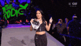 a woman is holding a trophy in front of a sign that says the rodic
