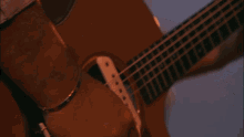 a close up of a person playing a guitar with a purple background