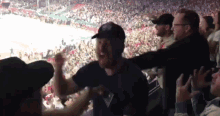 a crowd of people watching a hockey game with a man wearing a black hat