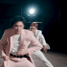a man in a pink suit is dancing with another man in white