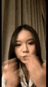 a girl with long hair is blowing a kiss with her hands .