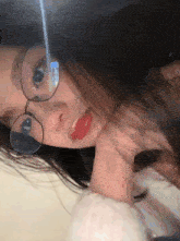 a woman wearing glasses and red lipstick is taking a selfie