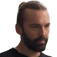 a man with a beard and hair in a bun looks at the camera