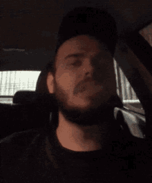 a man with a beard is smoking a cigarette in the back seat of a car