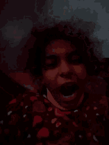a close up of a woman 's face with curly hair in the dark .