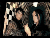 two women are standing next to each other in a hallway with checkered walls .