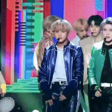 a man in a blue jacket is standing in front of a group of men in green jackets
