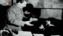 a man in a military uniform is shaking hands with a little girl .