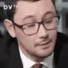 a man wearing glasses and a suit is making a funny face .