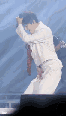 a man in a white shirt holds a microphone in his hand while dancing on a stage
