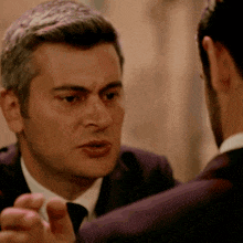 a man in a suit and tie is talking to another man in a suit