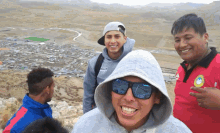 a man wearing sunglasses and a hooded sweatshirt is smiling for a picture