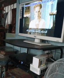 a tcl television is sitting on a desk in front of a window