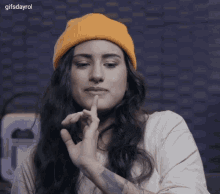 a woman wearing a yellow beanie and a tattoo on her arm