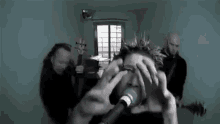 a man with a mohawk is singing into a microphone while another man plays a guitar .