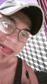 a man wearing glasses and a baseball cap is taking a selfie
