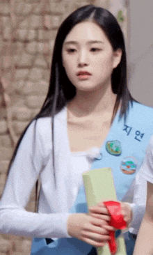a girl with long black hair is wearing a white shirt and a blue vest with chinese writing on it .