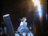 a woman is standing in front of a fan while a flame is coming out of it .