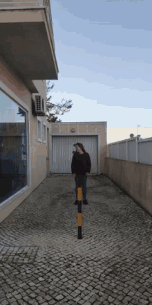 a woman stands in a narrow alleyway next to a building
