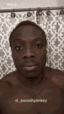 a man without a shirt is standing in front of a shower curtain and has a tiktok account