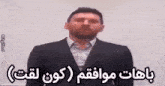 a man in a suit and tie is standing in front of a white board with arabic writing .