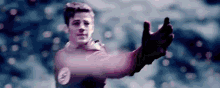 a young man in a superhero costume is reaching out his hand towards the camera .